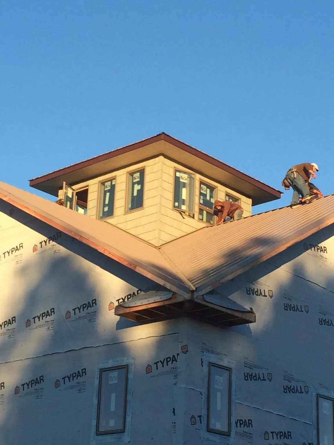 Roofers working around a rooftop cupola on a new metal roof at sunset — Roof Waterproofing in Scottsburg by Roofing Brothers